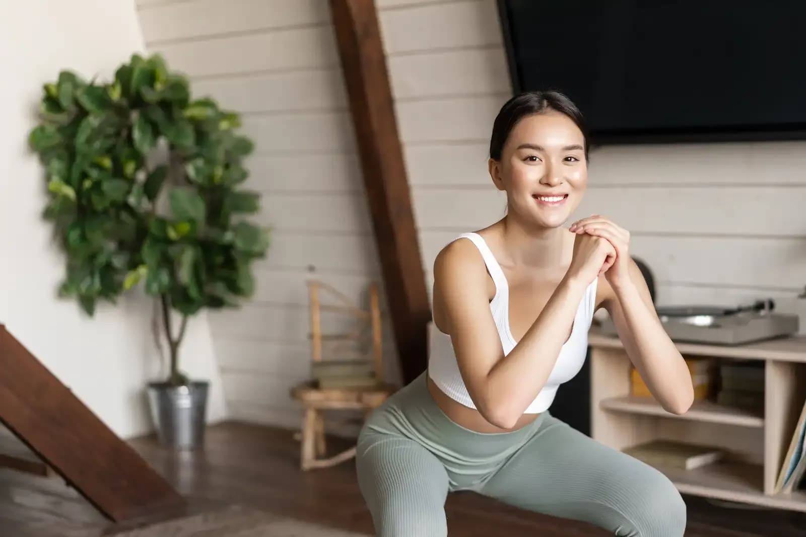 A fit, young woman happily doing squats during a home workout