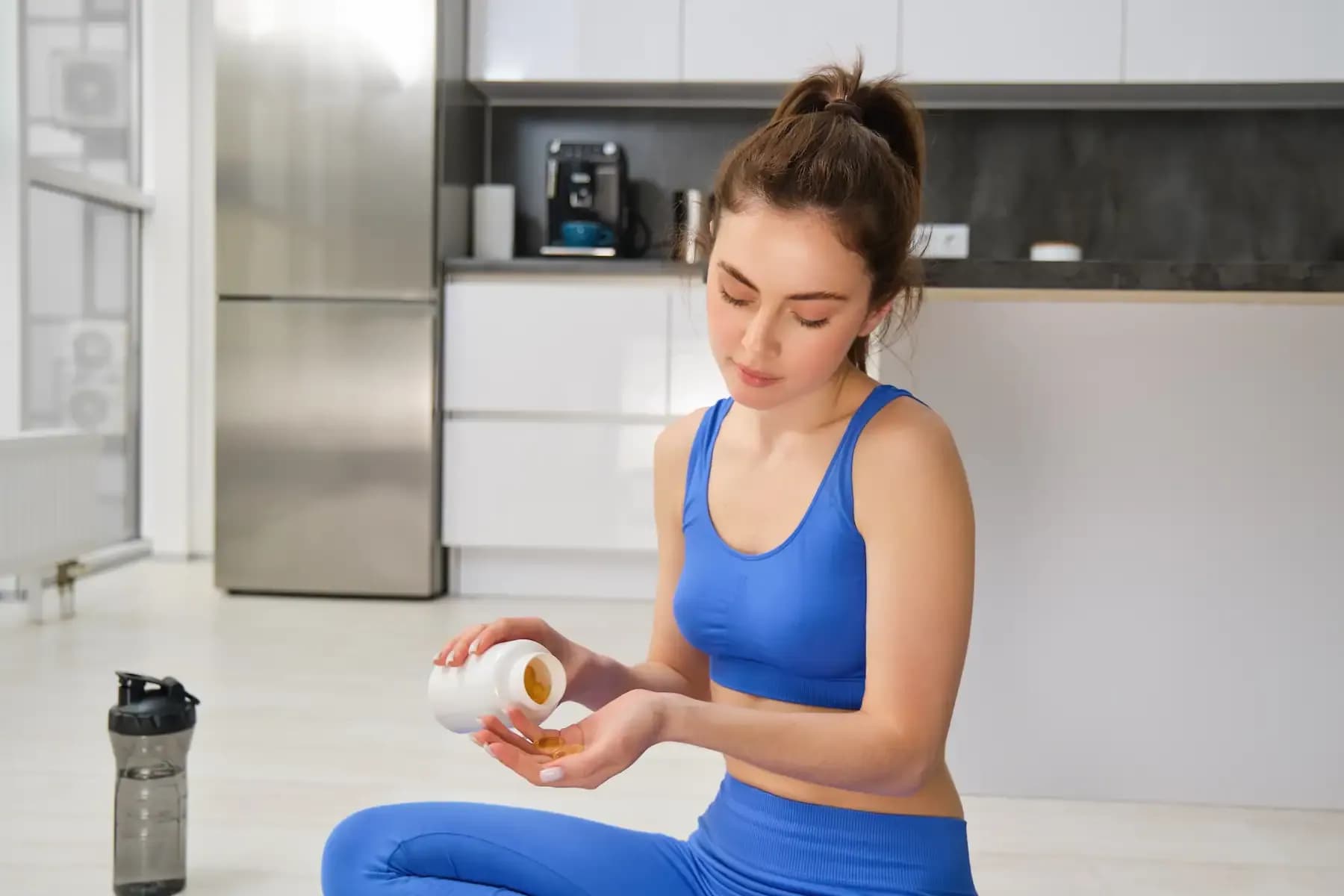 A young woman in athletic wear getting a capsule from a medicine bottle